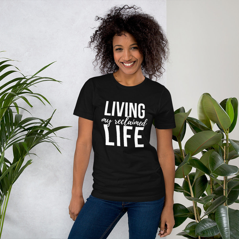 A black unisex t-shirt with "Living My Reclaimed Life" text in white modern script.